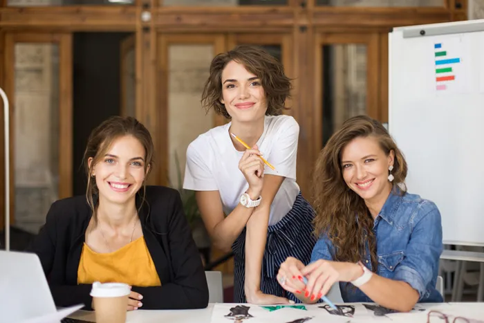 Drei glückliche Frauen in einem harmonisch gestalteten Büro – Feng Shui für Gesundheit und Unternehmenserfolg