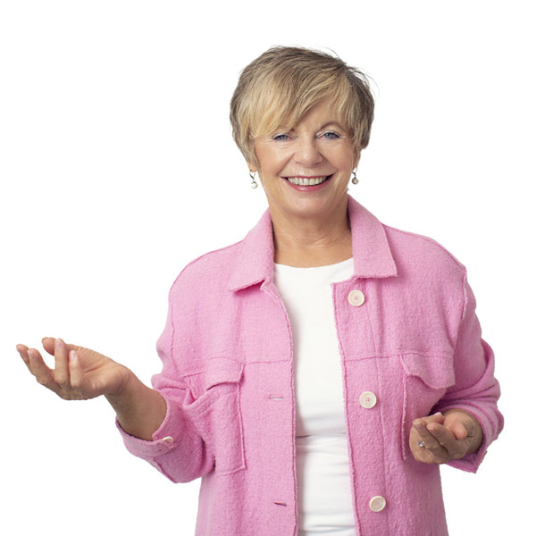 Jacqueline Franke vor einer Hauswand mit einladender Geste – Expertin für energetische Raumgestaltung und Feng Shui für Unternehmen