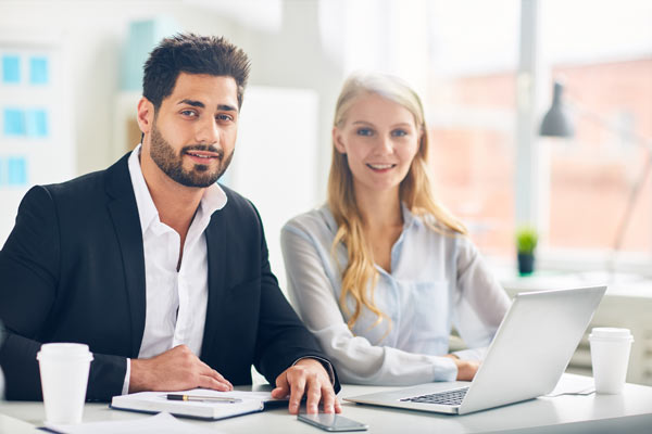 Mann und Frau sitzen entspannt am Schreibtisch, Ihr Vertrauen in Feng Shui und Geomantie